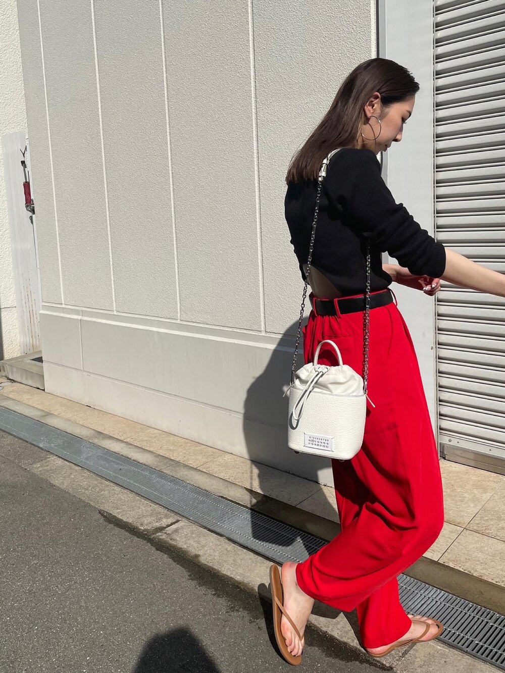 ブラック系のTシャツ/カットソー、レッド系のスラックス、ブラウン系のサンダルを着用したレディースの春コーディネートの3枚目の写真