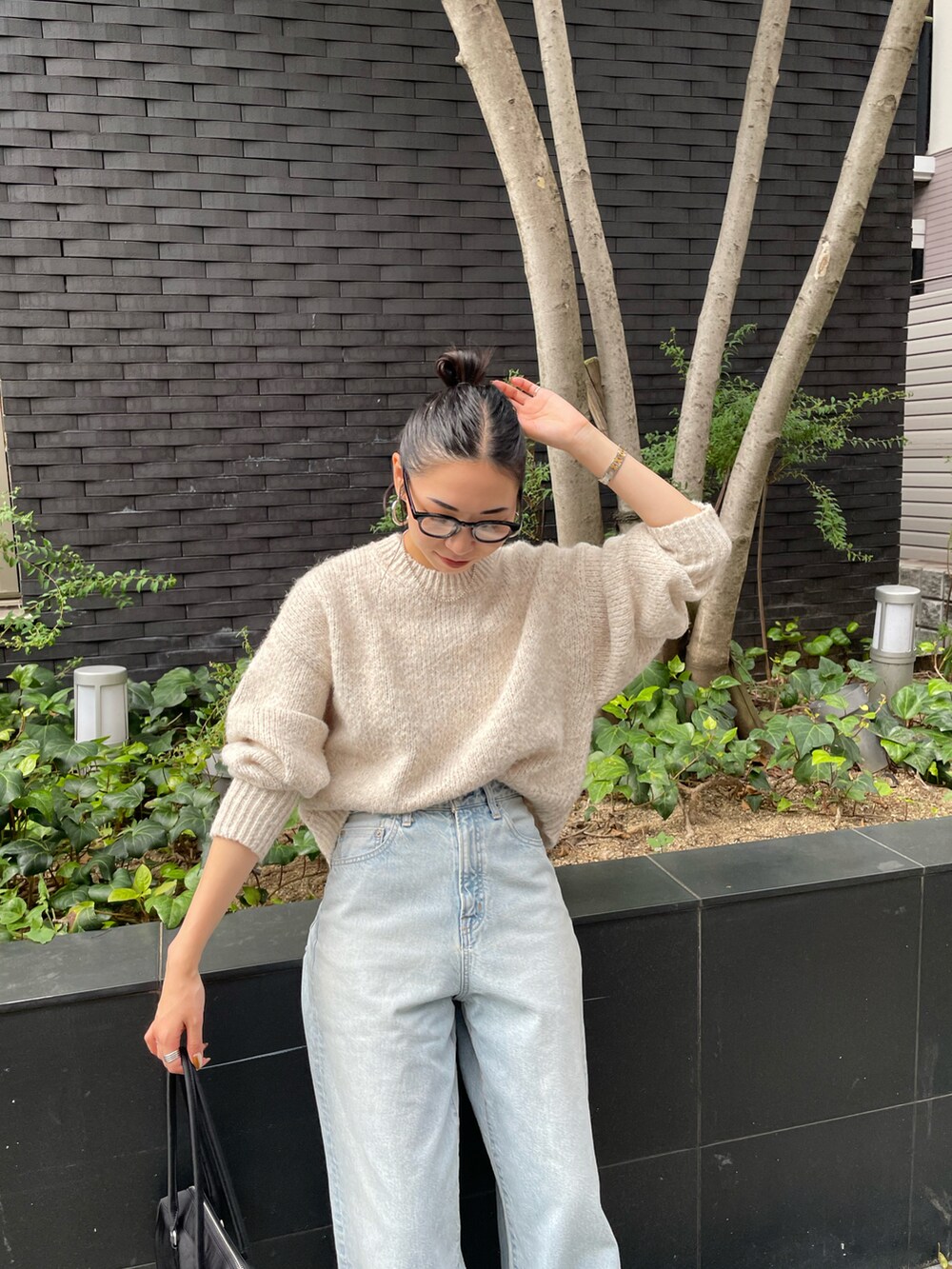 ブルー系のデニムパンツ、ホワイト系のニット/セーター、ブラック系のスニーカーを着用したレディースの秋コーディネートの5枚目の写真