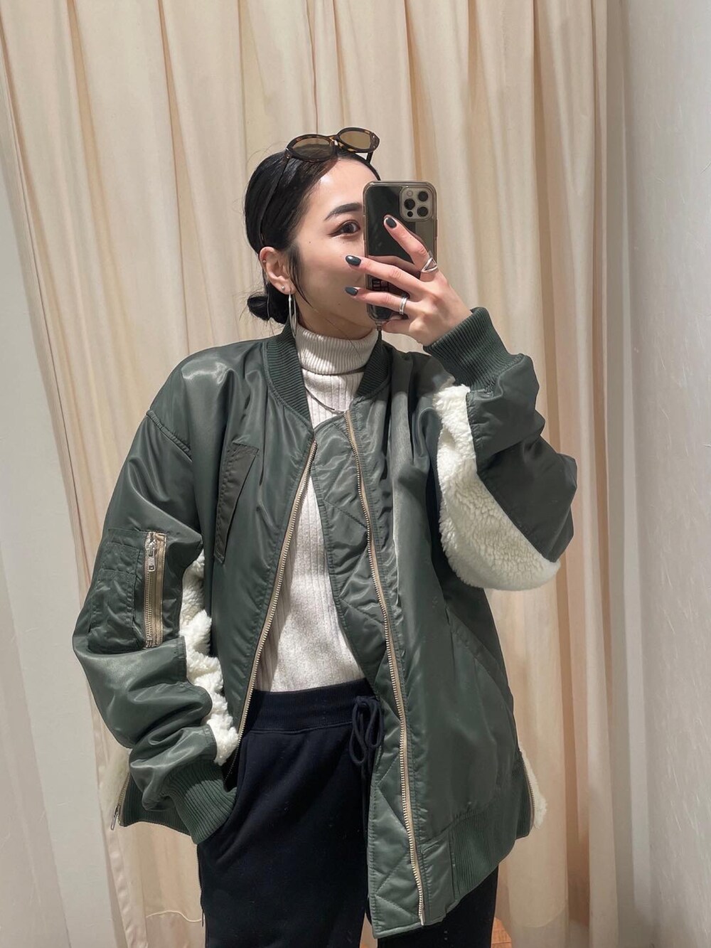 グリーン系のMA-1、ホワイト系のニット/セーター、ブラック系のスウェットパンツを着用したレディースの冬コーディネートの5枚目の写真