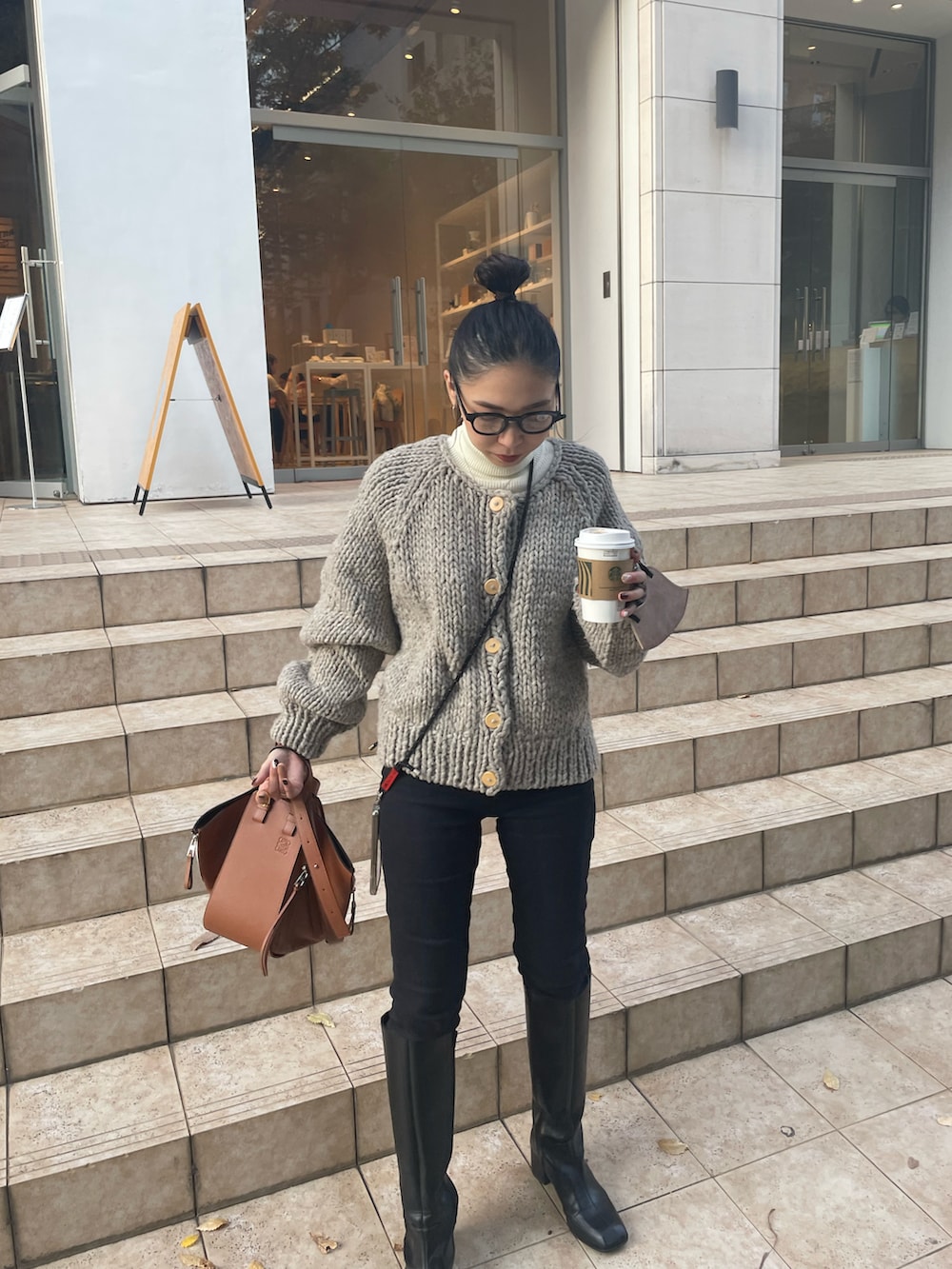 ブラウン系のバックパック/リュック、ブラック系のデニムパンツ、ブラック系のブーツを着用したレディースの秋コーディネートの4枚目の写真