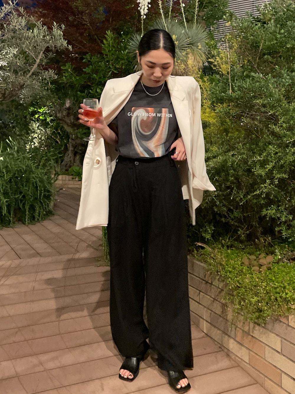 ブラック系のスラックス、ブラック系のサンダル、ホワイト系のテーラードジャケットを着用したレディースの夏コーディネートの2枚目の写真