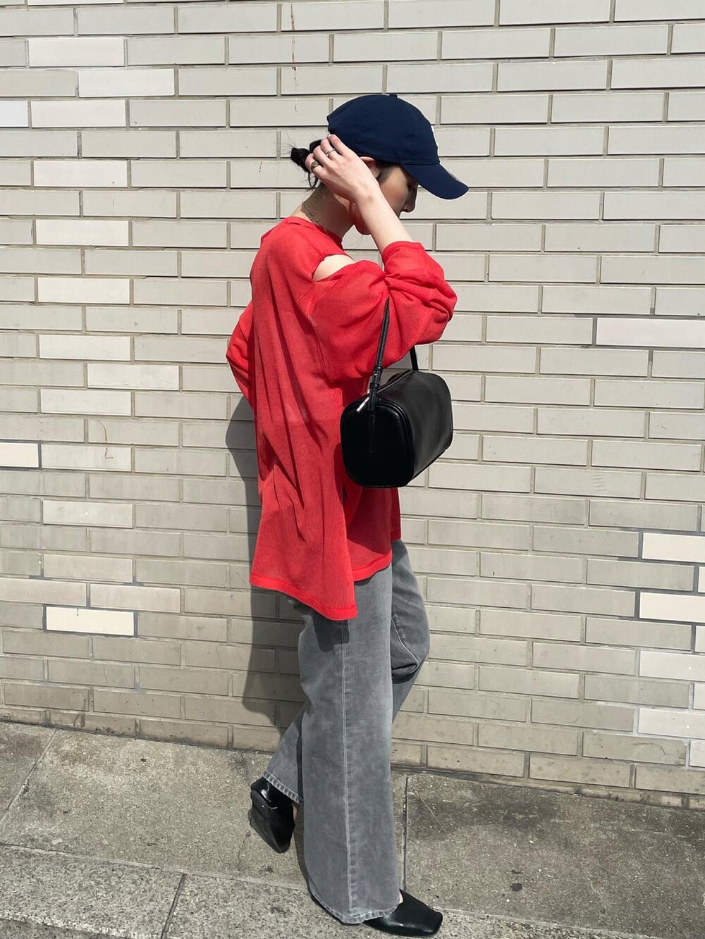 ブラック系のデニムパンツ、ブラック系のハンドバッグ、オレンジ系のニット/セーターを着用したレディースの冬コーディネートの2枚目の写真
