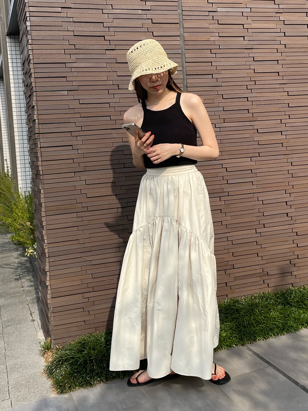 ブラック系のタンクトップ、ホワイト系のスカート、ブラック系のサンダルを着用したレディースの夏コーディネートの3枚目の写真