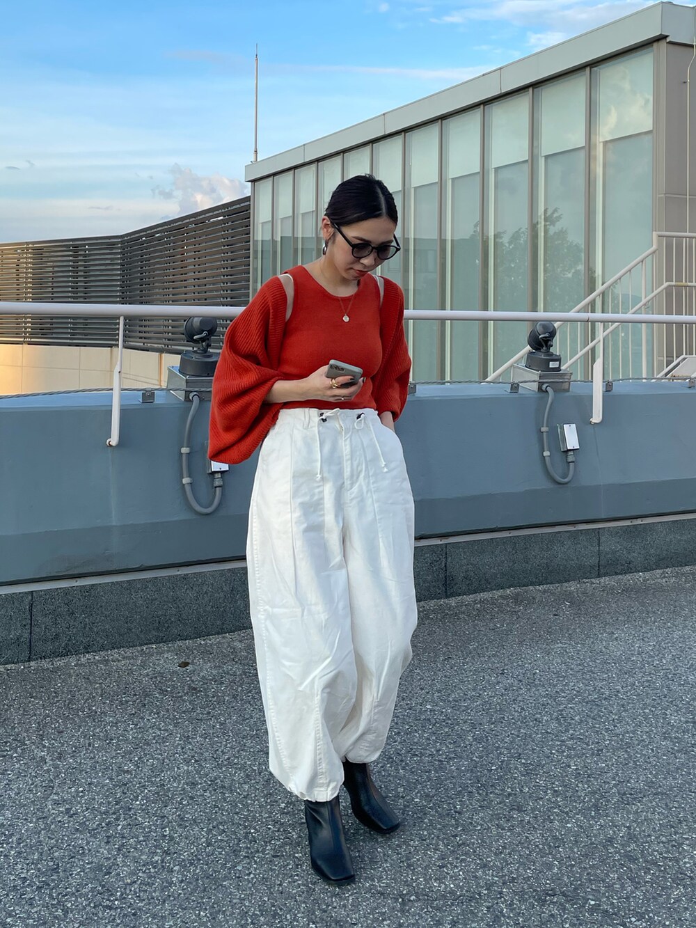 オレンジ系のカーディガン/ボレロ、ホワイト系のその他パンツ、ブラック系のブーツを着用したレディースの秋コーディネートの5枚目の写真