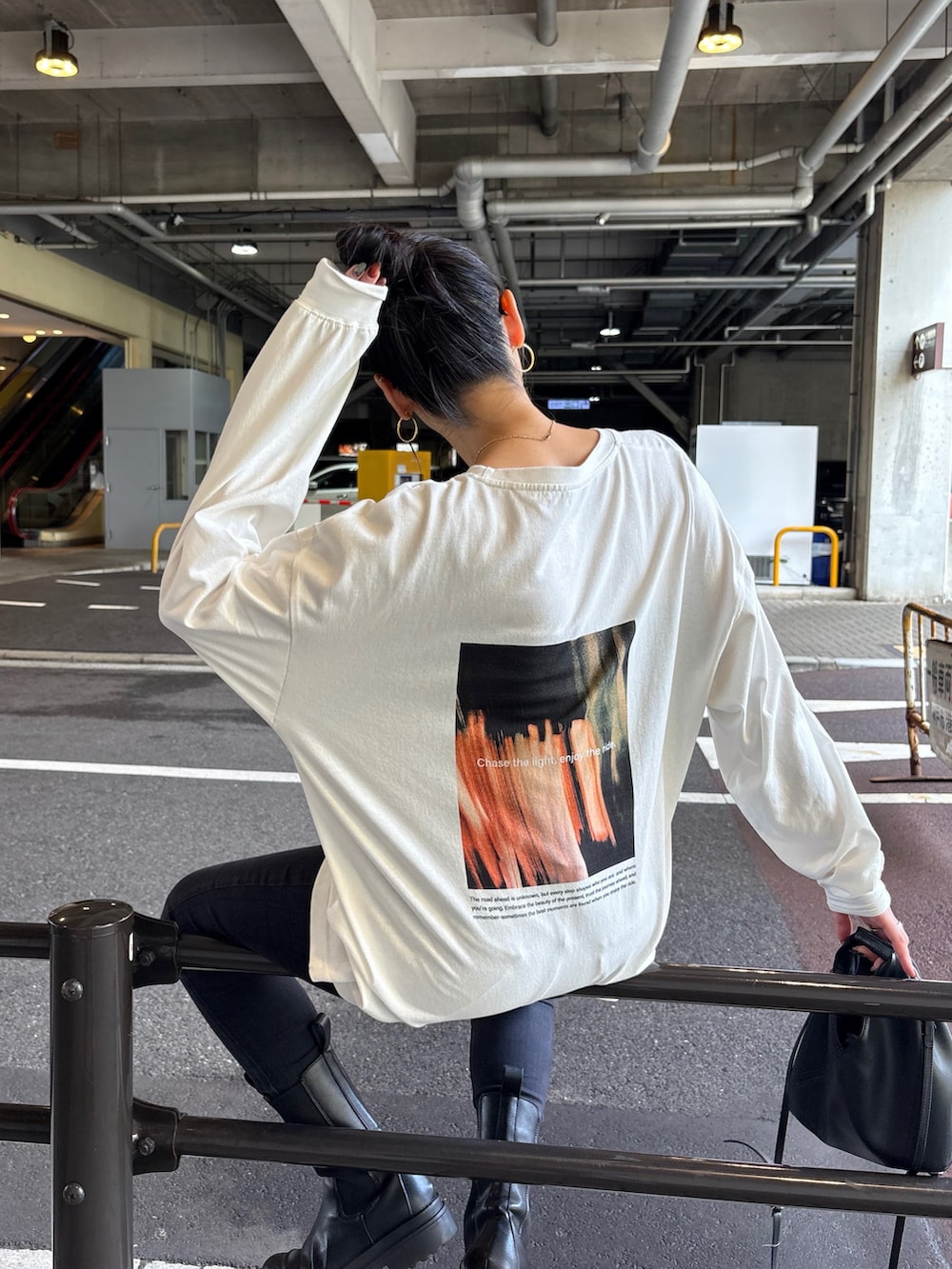 ブラック系のデニムパンツ、ブラック系のブーツ、ブラック系のショルダーバッグを着用したレディースの秋コーディネートの2枚目の写真