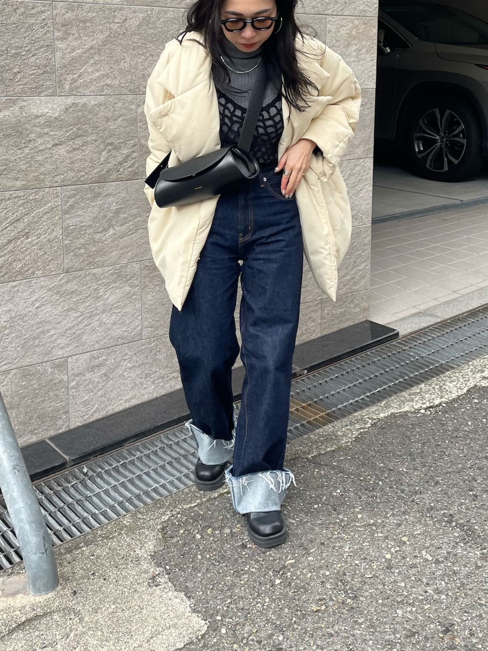 ブラック系のショルダーバッグ、ブルー系のデニムパンツ、ホワイト系のダウンジャケット/コートを着用したレディースの冬コーディネートの3枚目の写真