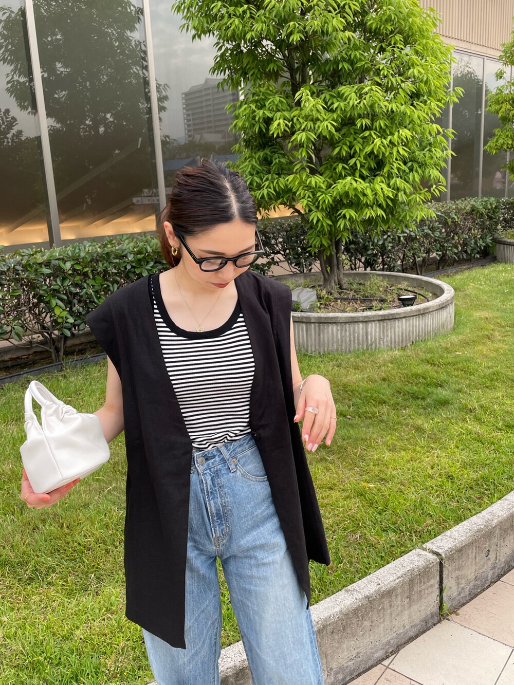 ホワイト系のタンクトップ、ブラック系のベスト、ブルー系のデニムパンツを着用したレディースの夏コーディネートの4枚目の写真