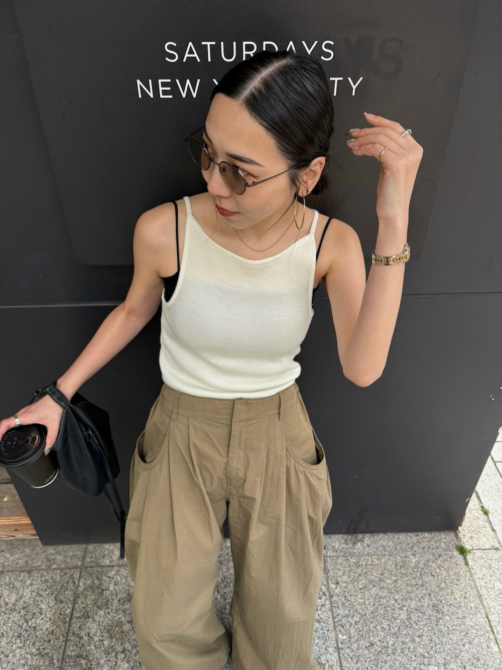 ブラック系のショルダーバッグ、ブラック系のサンダル、シルバー系のピアス（両耳用）を着用したレディースの春コーディネートの3枚目の写真