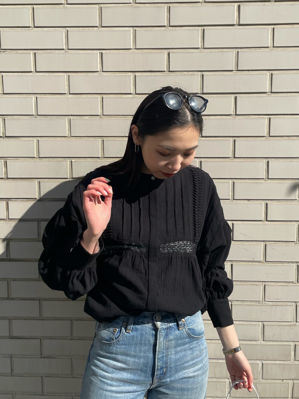 ブルー系のデニムパンツ、ホワイト系のハンドバッグ、ブラック系のシャツ/ブラウスを着用したレディースの冬コーディネートの5枚目の写真