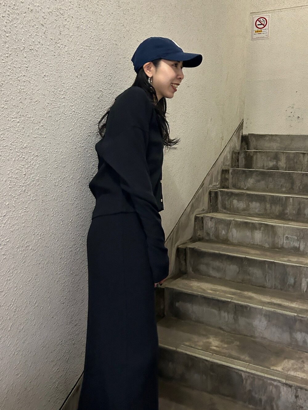 ブラック系のワンピース、ブラック系のブーツ、ブルー系のキャップを着用したレディースの春コーディネートの5枚目の写真