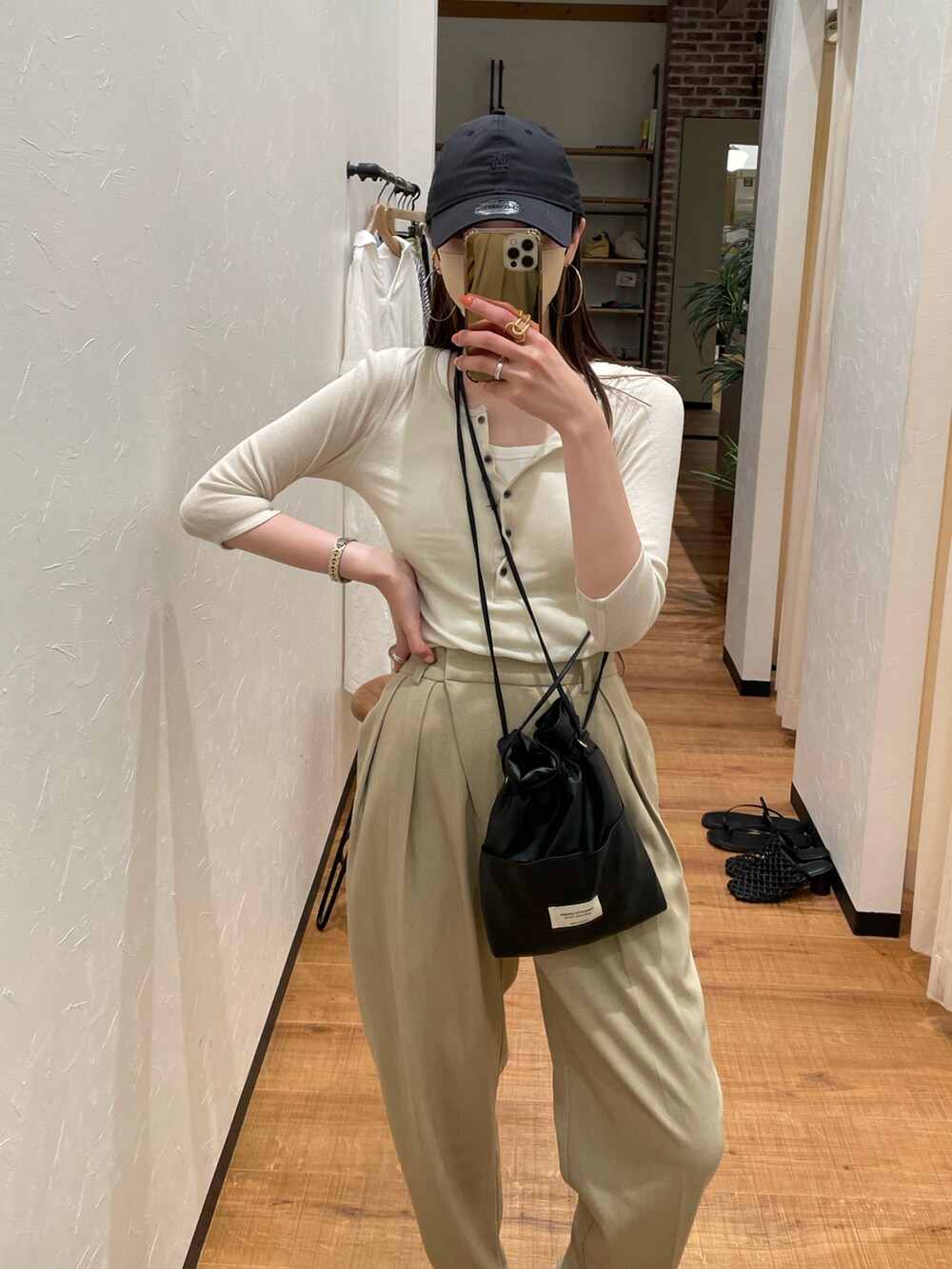 ベージュ系のTシャツ/カットソー、ベージュ系のスラックス、ブラック系のショルダーバッグを着用したレディースの夏コーディネートの2枚目の写真