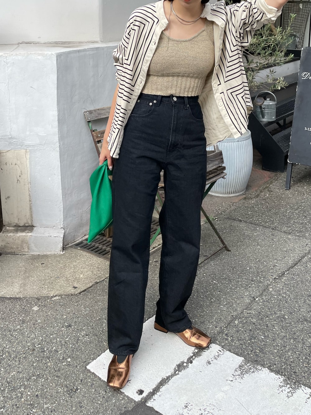 ブラック系のデニムパンツ、グリーン系のショルダーバッグ、ゴールド系のパンプスを着用したレディースの秋コーディネートの3枚目の写真