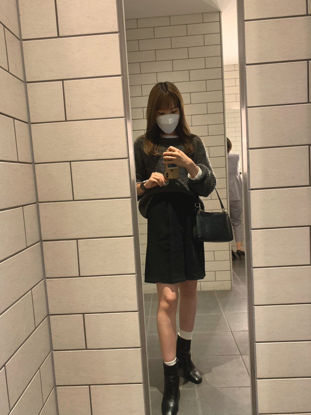 ブラック系のパンツ、ブラック系のブーツ、グレー系のニット/セーターを着用したレディースの秋コーディネートの2枚目の写真