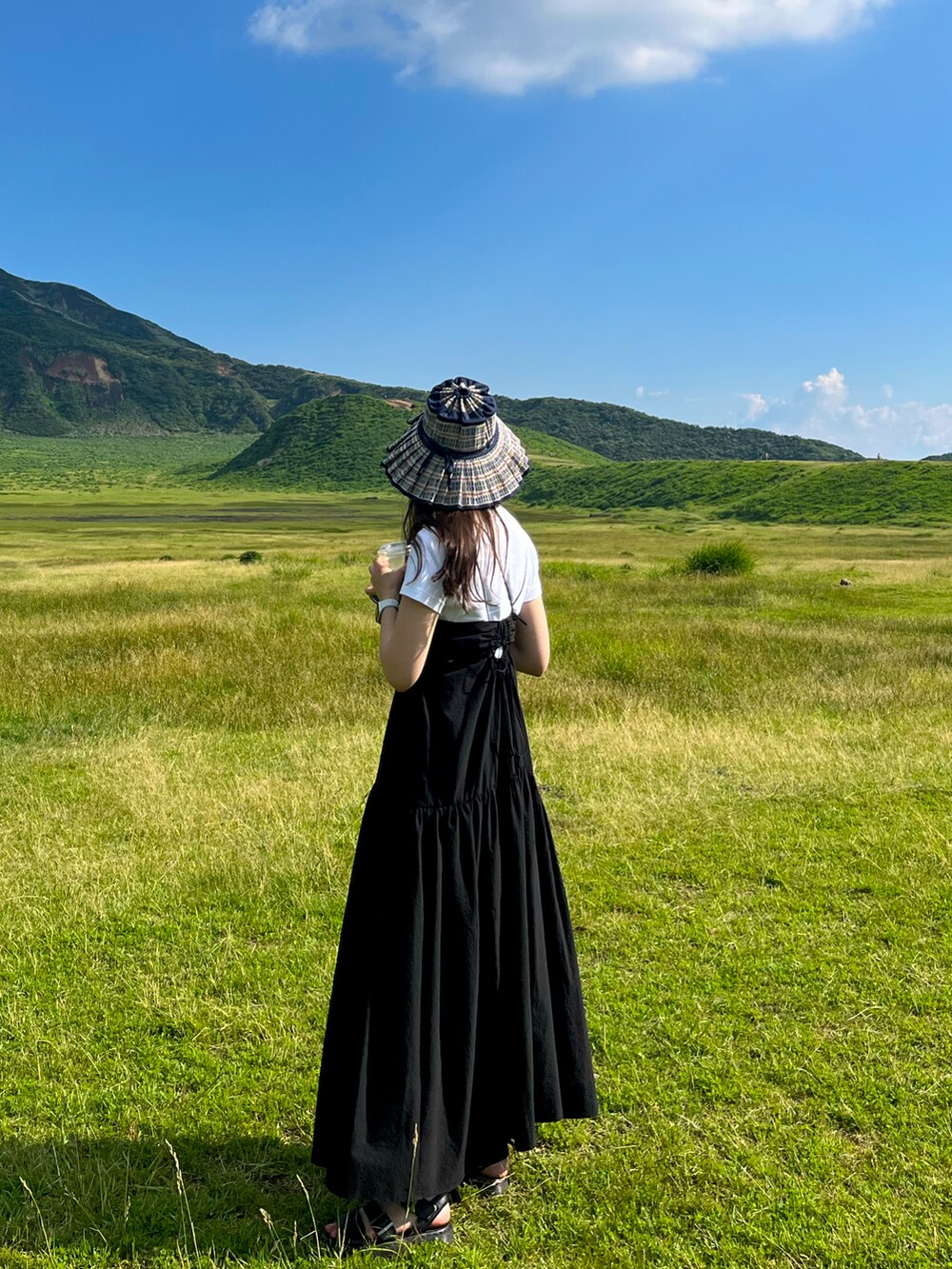 ブラック系のサンダル、ブラック系のワンピース、ブルー系のハットを着用したレディースの夏コーディネートの2枚目の写真