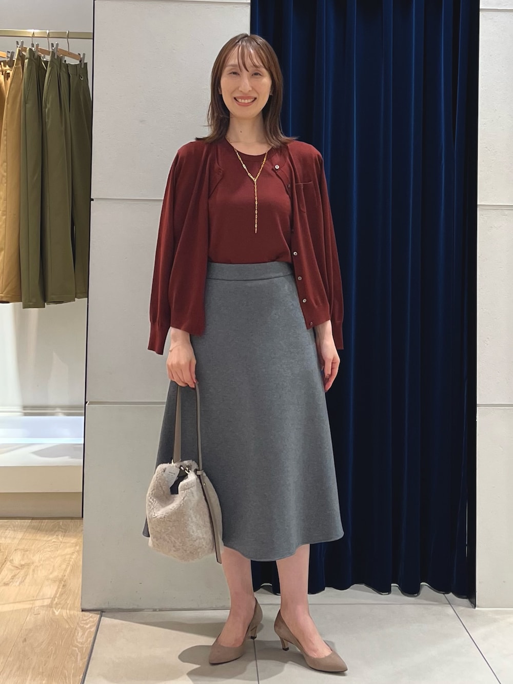 レッド系のニット/セーター、レッド系のカーディガン/ボレロ、グレー系のスカートを着用したレディースの秋コーディネートの6枚目の写真