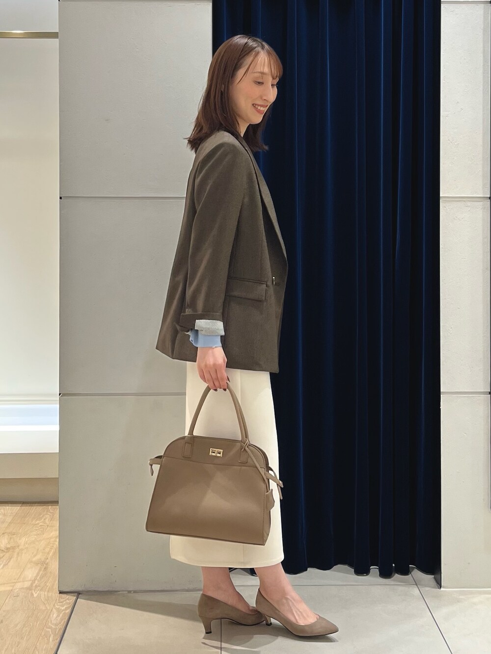 ブラウン系のテーラードジャケット、ブルー系のニット/セーター、ホワイト系のスカートを着用したレディースの秋コーディネートの8枚目の写真