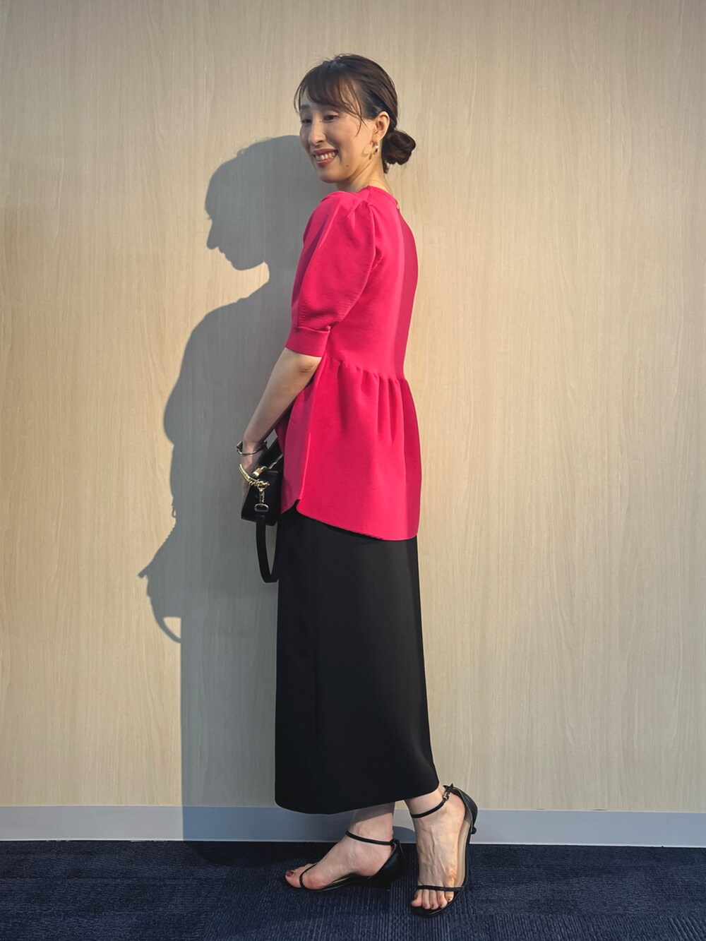 ピンク系のニット/セーター、ブラック系のショルダーバッグ、ブラック系のスカートを着用したレディースの夏コーディネートの4枚目の写真