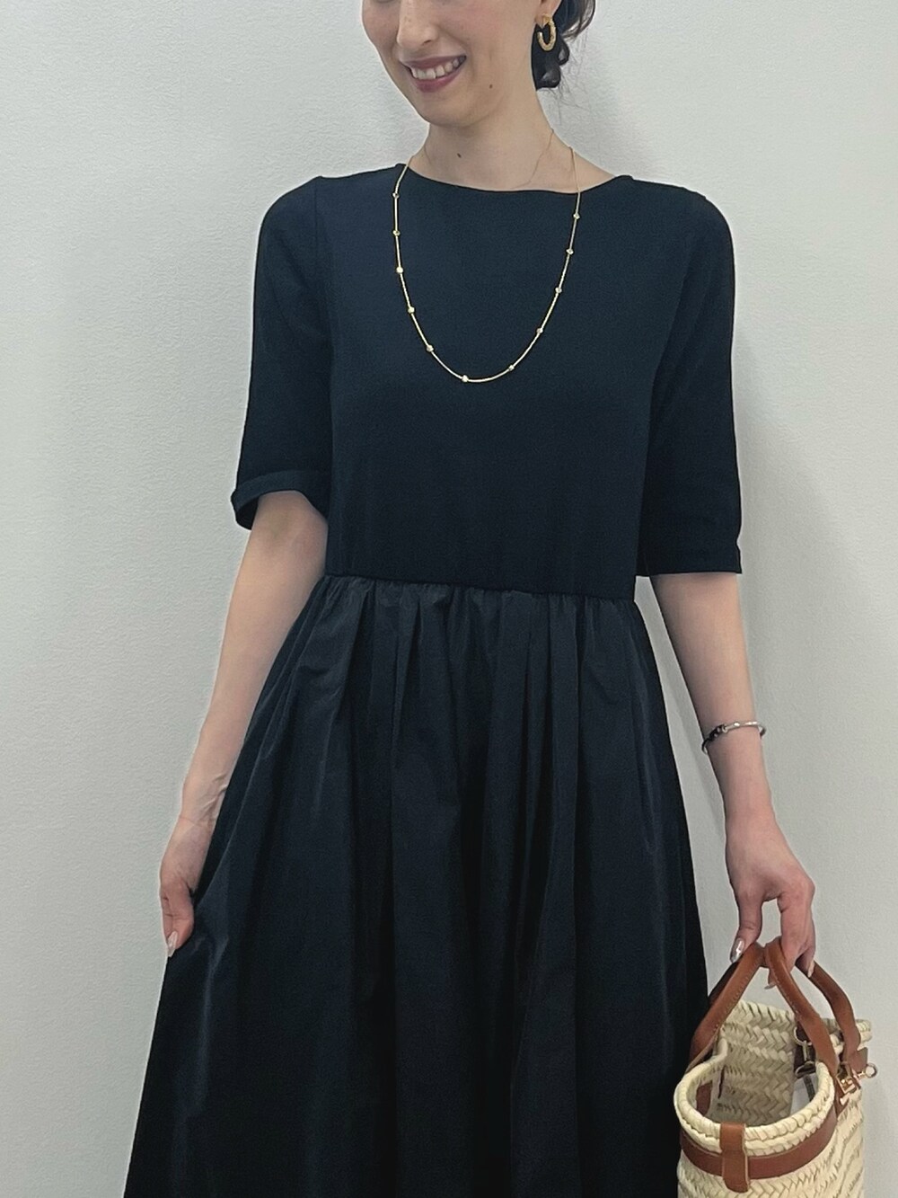 ブラック系のワンピース、ブラウン系のかごバッグ、ブラック系のサンダルを着用したレディースの春コーディネートの3枚目の写真