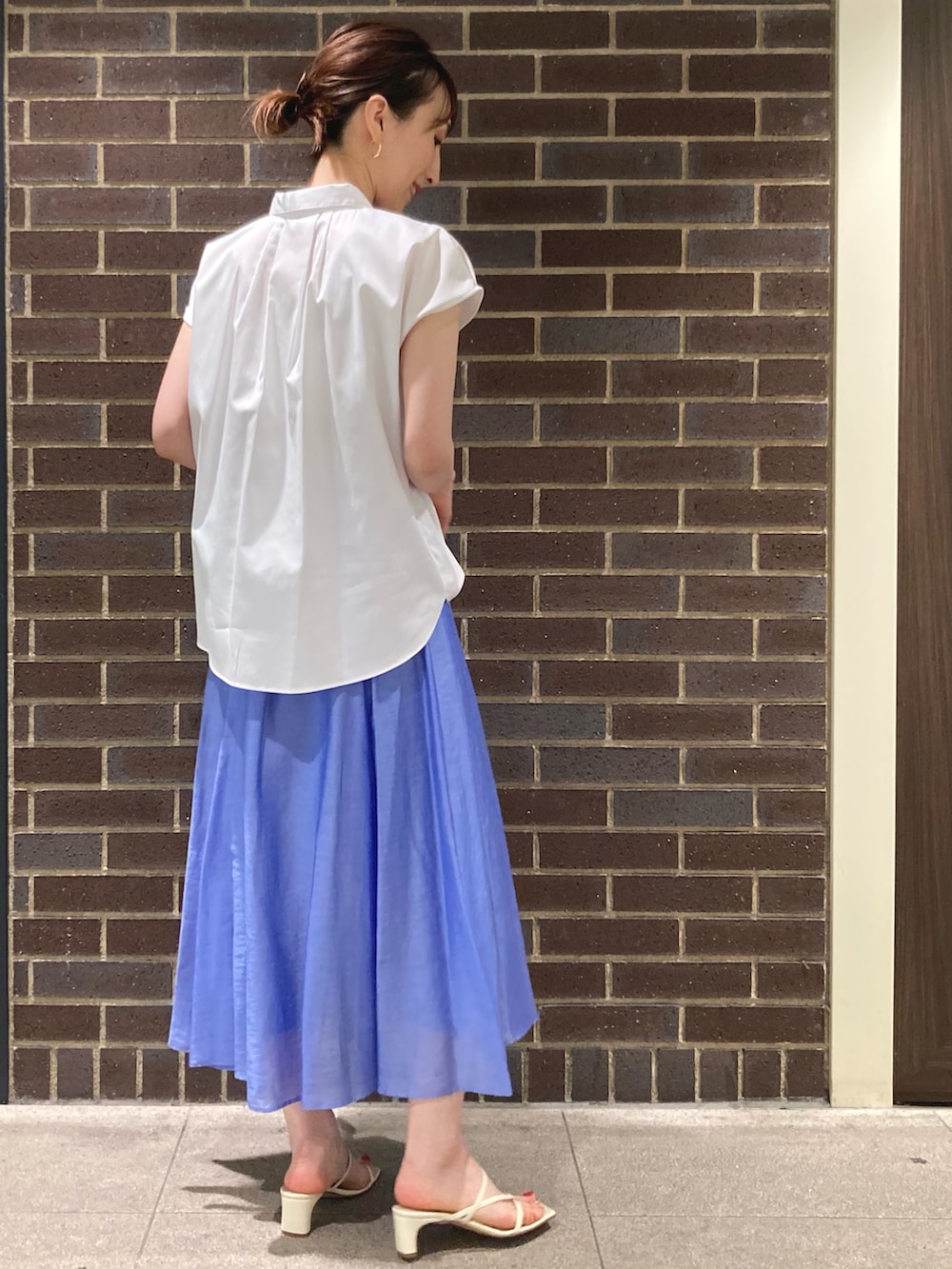 ホワイト系のシャツ/ブラウス、ブルー系のスカート、ベージュ系のサンダルを着用したレディースの春コーディネートの3枚目の写真