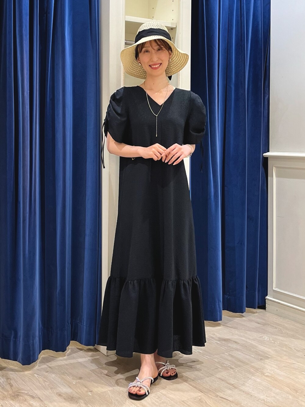 シルバー系のサンダル、ブラック系のワンピース、ベージュ系のハットを着用したレディースの春コーディネートの3枚目の写真