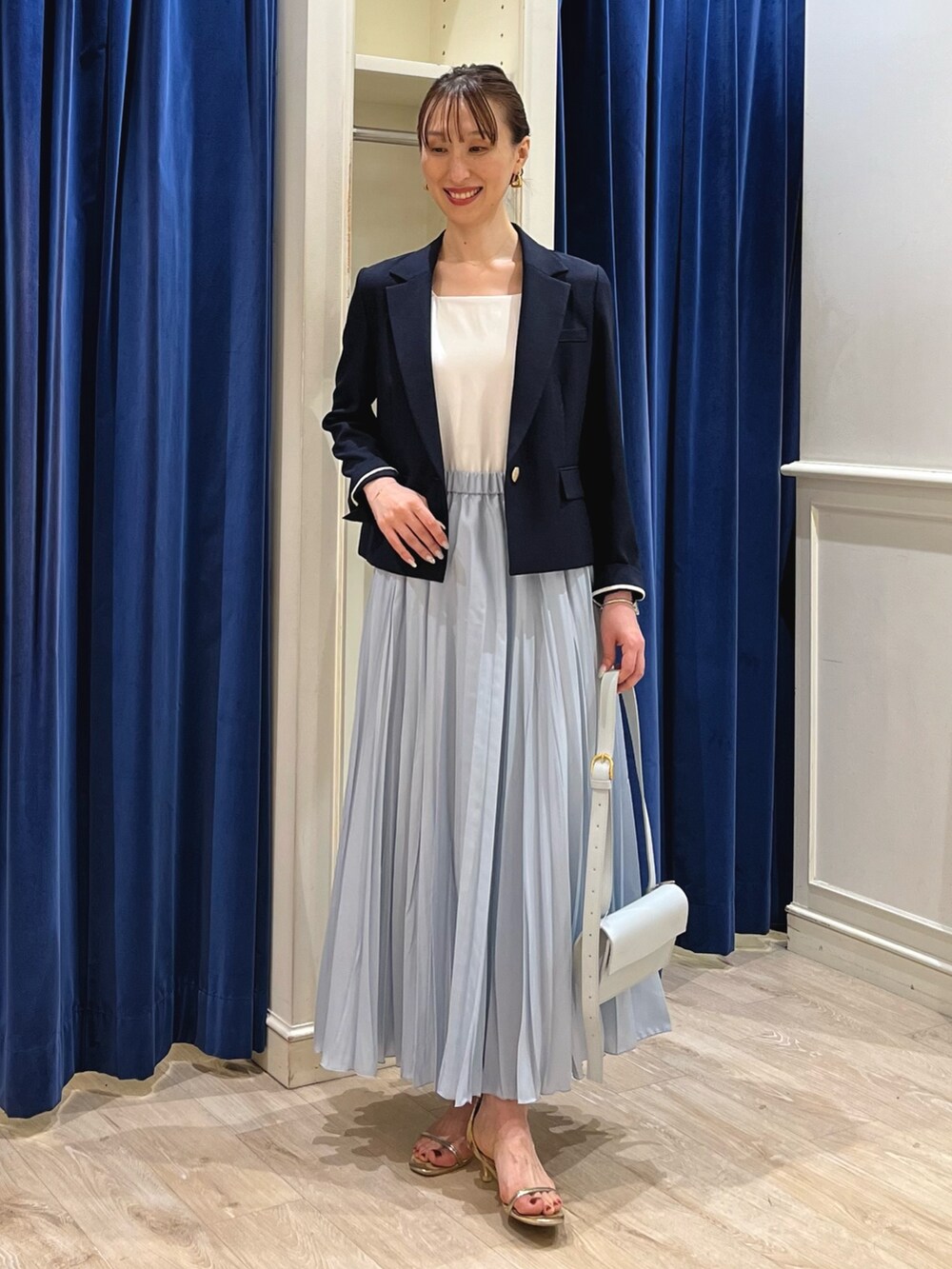 ブルー系のテーラードジャケット、ホワイト系のタンクトップ、ブルー系のスカートを着用したレディースの夏コーディネートの7枚目の写真