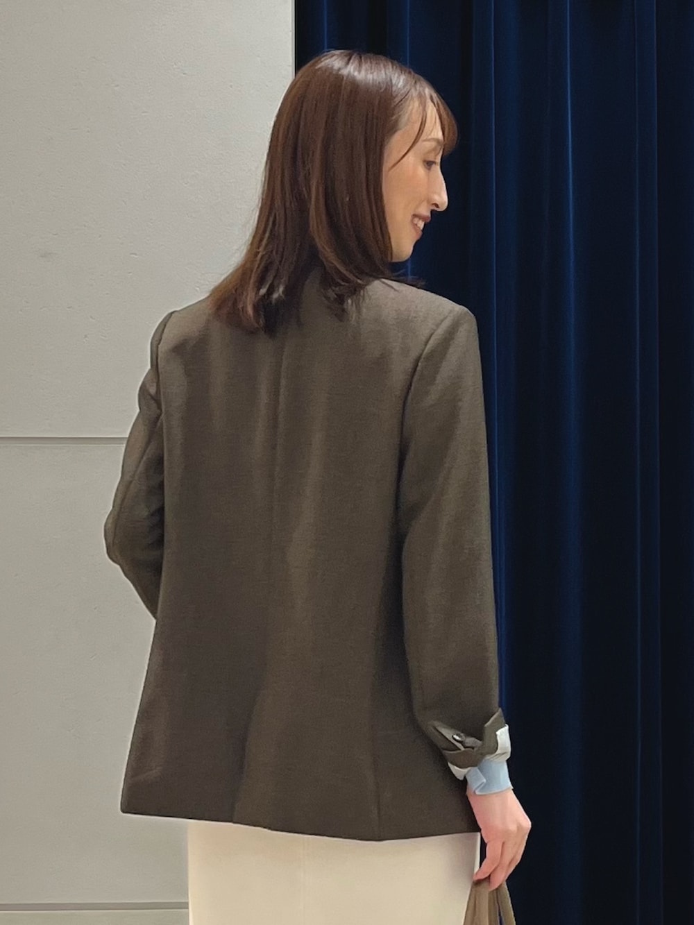 ブラウン系のテーラードジャケット、ブルー系のニット/セーター、ホワイト系のスカートを着用したレディースの秋コーディネートの4枚目の写真