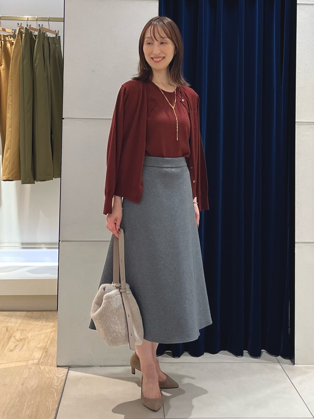 レッド系のニット/セーター、レッド系のカーディガン/ボレロ、グレー系のスカートを着用したレディースの秋コーディネートの9枚目の写真