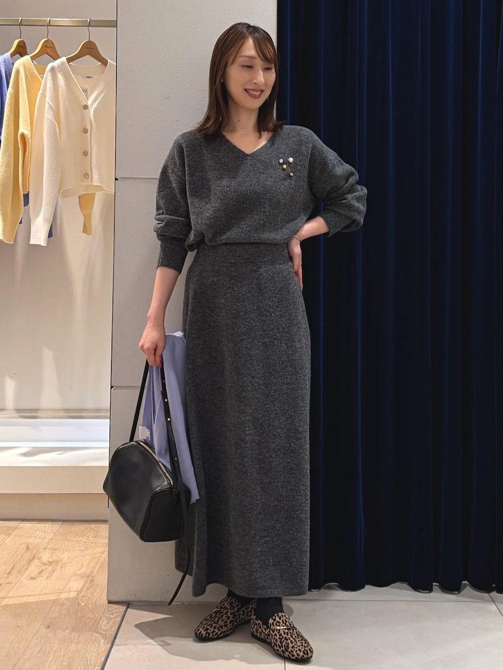 グレー系のニット/セーター、グレー系のスカート、ブラック系のショルダーバッグを着用したレディースの冬コーディネートの7枚目の写真