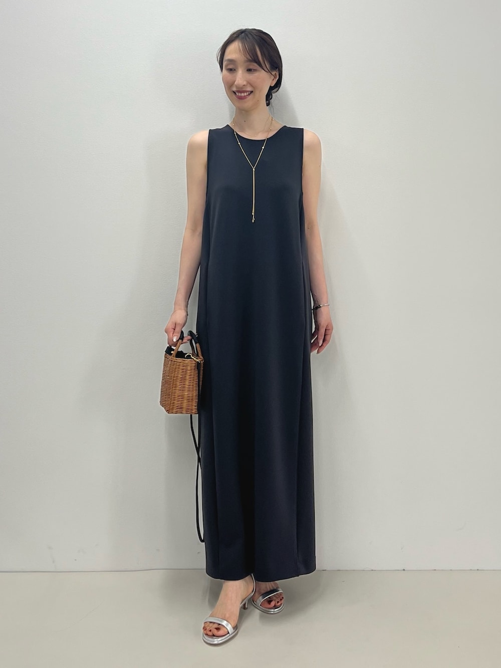 グレー系のワンピース、イエロー系のかごバッグ、シルバー系のサンダルを着用したレディースの春コーディネートの6枚目の写真