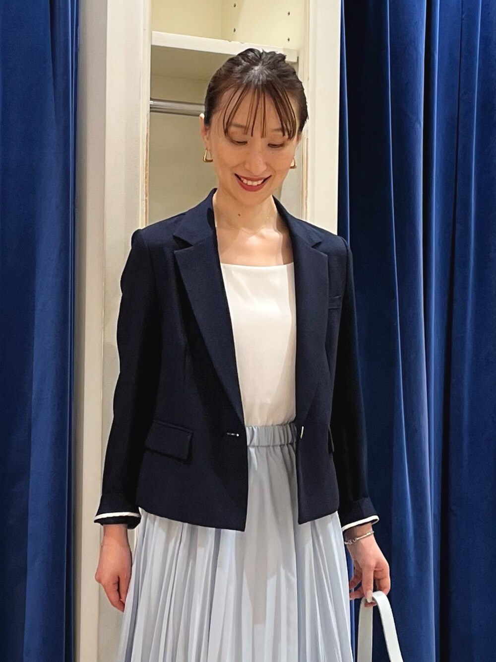 ブルー系のテーラードジャケット、ホワイト系のタンクトップ、ブルー系のスカートを着用したレディースの夏コーディネートの3枚目の写真