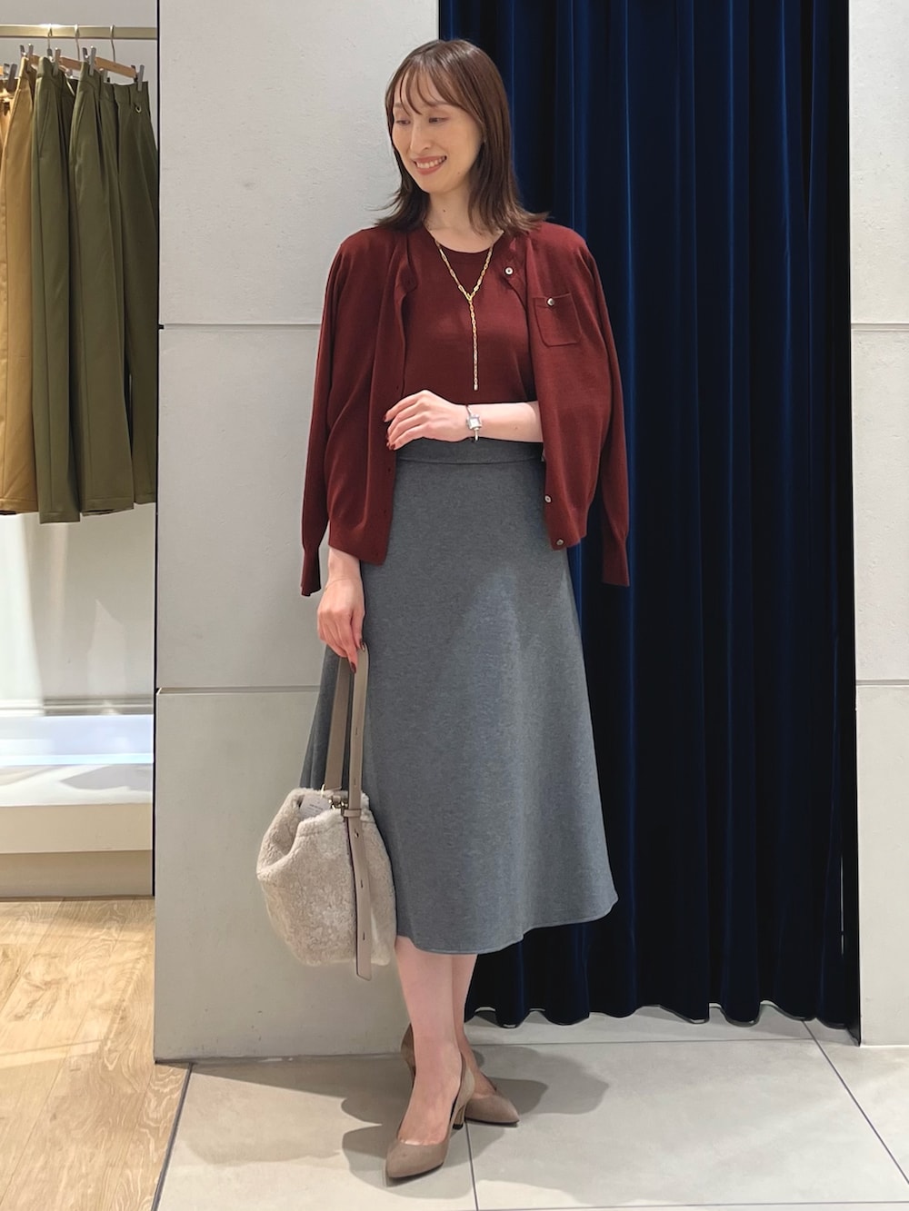 レッド系のニット/セーター、レッド系のカーディガン/ボレロ、グレー系のスカートを着用したレディースの秋コーディネートの2枚目の写真