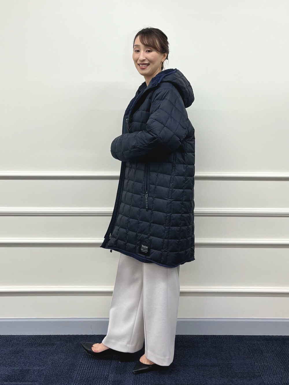 ブルー系のダウンジャケット/コート、ブラック系のニット/セーター、ベージュ系のその他パンツを着用したレディースの秋コーディネートの4枚目の写真