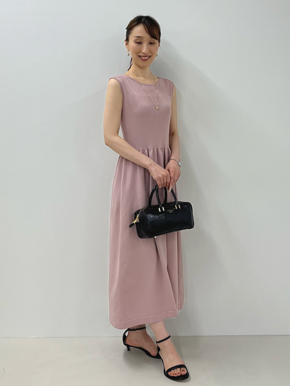 ピンク系のワンピース、ブラック系のサンダル、ゴールド系のピアス(両耳用)を着用したレディースの夏コーディネートの5枚目の写真