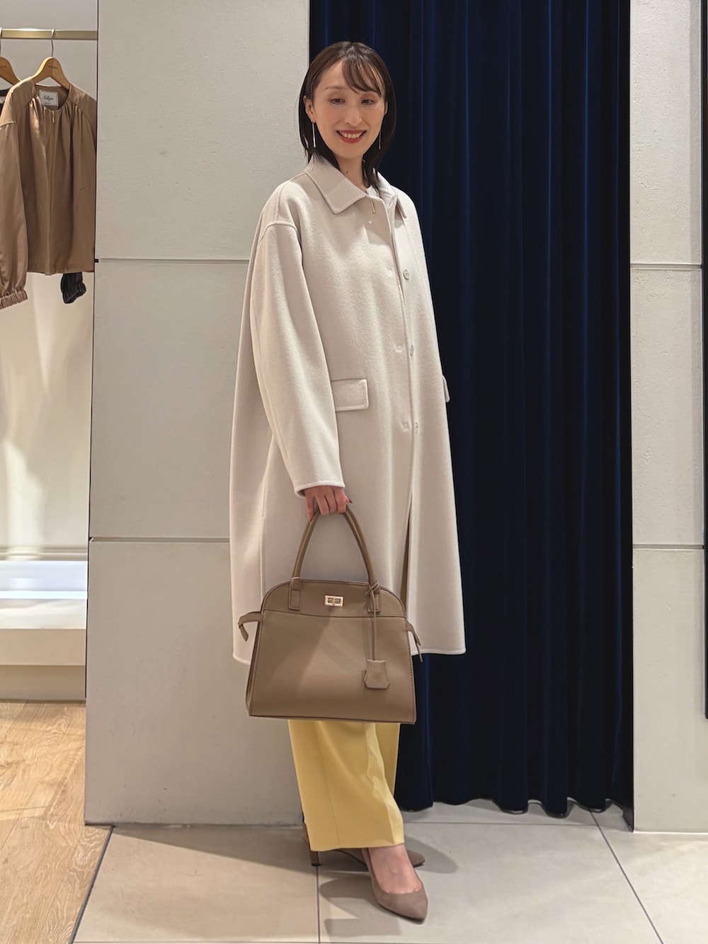 ベージュ系のステンカラーコート、ホワイト系のTシャツ/カットソー、イエロー系のその他パンツを着用したレディースの秋コーディネートの6枚目の写真