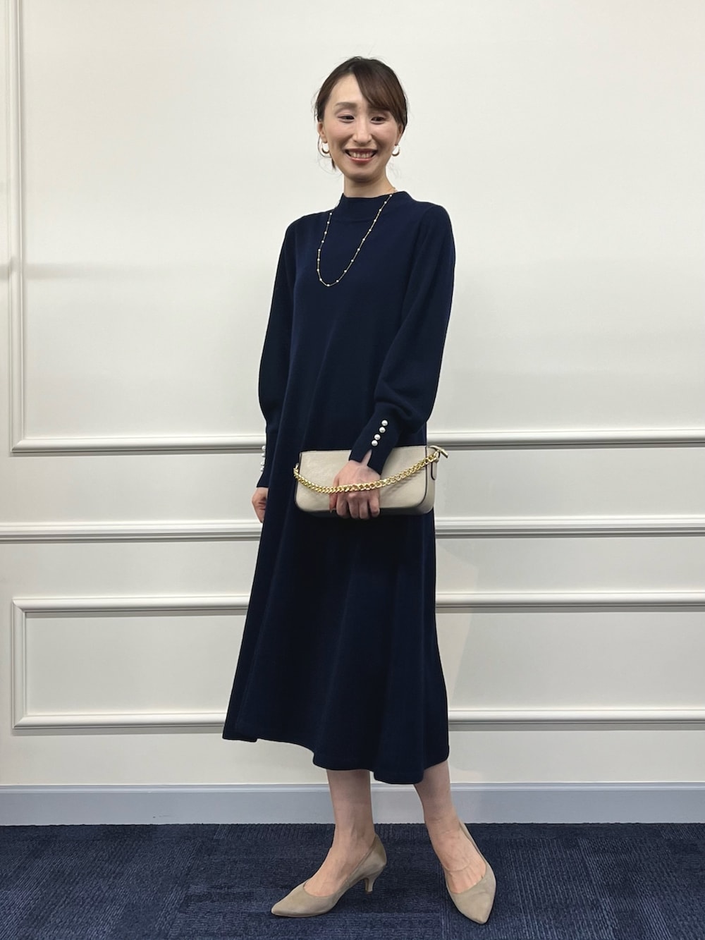 ベージュ系のショルダーバッグ、ブルー系のワンピース、ゴールド系のネックレスを着用したレディースの冬コーディネートの3枚目の写真