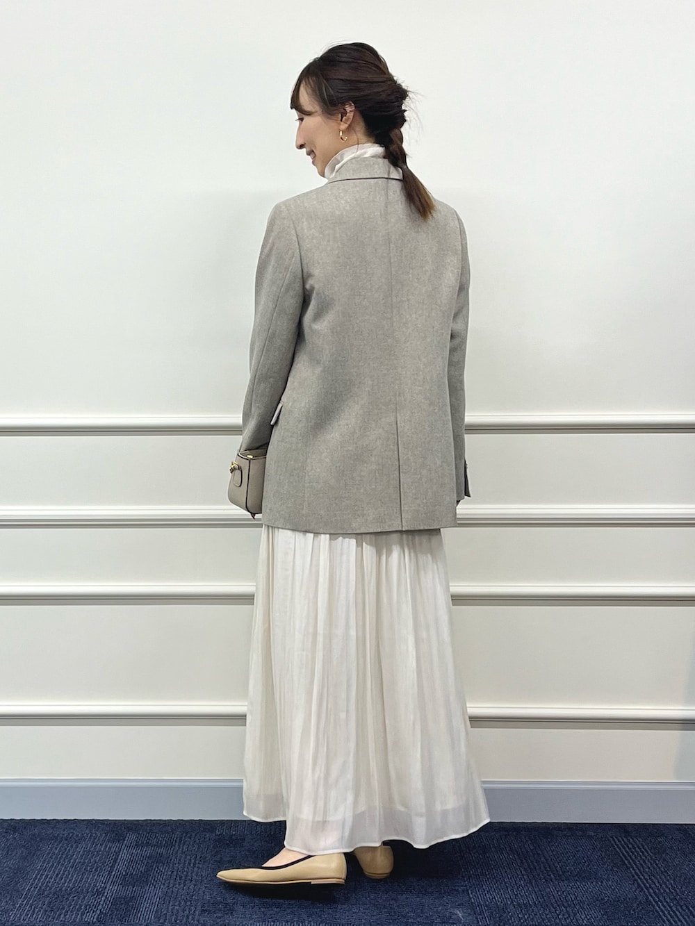 ゴールド系のニット/セーター、ベージュ系のテーラードジャケット、ホワイト系のスカートを着用したレディースの秋コーディネートの5枚目の写真