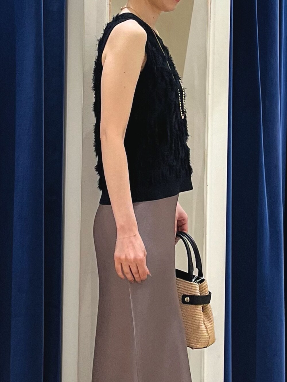 ブラック系のニット/セーター、グリーン系のスカート、ブラック系のかごバッグを着用したレディースの春コーディネートの5枚目の写真