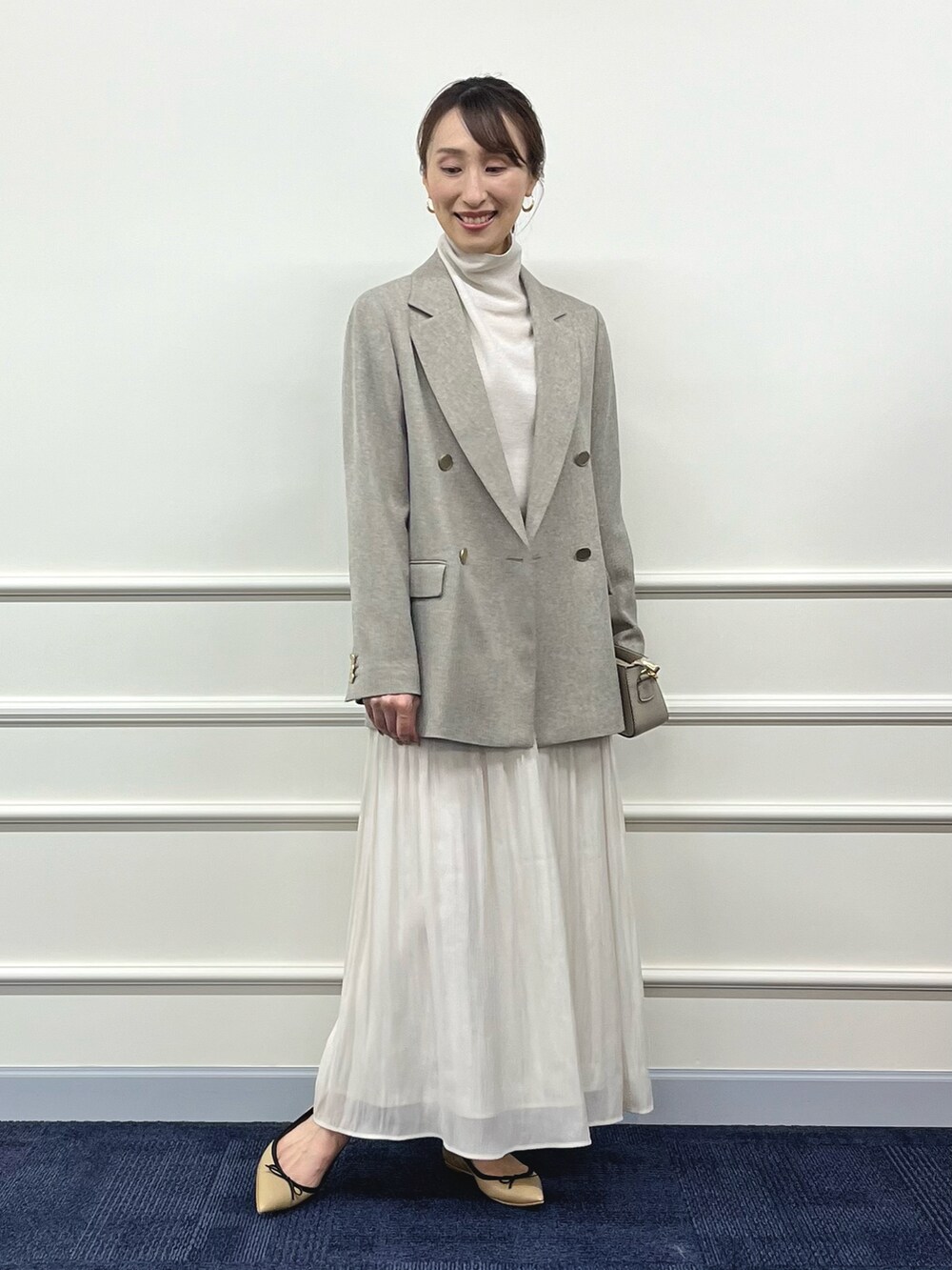 ゴールド系のニット/セーター、ベージュ系のテーラードジャケット、ホワイト系のスカートを着用したレディースの秋コーディネートの3枚目の写真