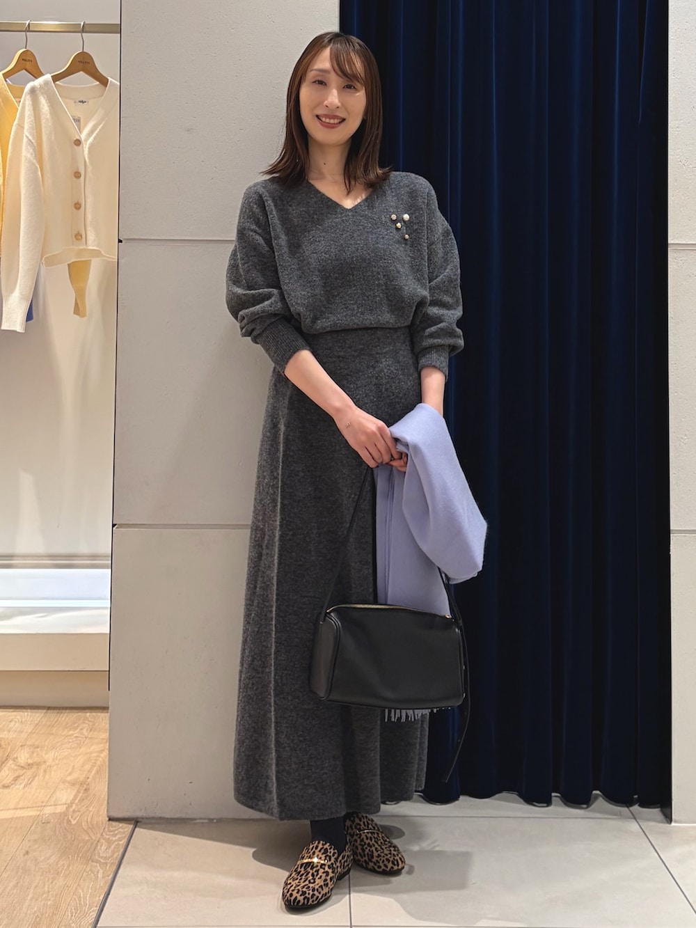 グレー系のニット/セーター、グレー系のスカート、ブラック系のショルダーバッグを着用したレディースの冬コーディネートの6枚目の写真