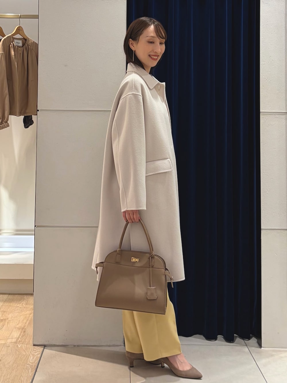 ベージュ系のステンカラーコート、ホワイト系のTシャツ/カットソー、イエロー系のその他パンツを着用したレディースの秋コーディネートの10枚目の写真