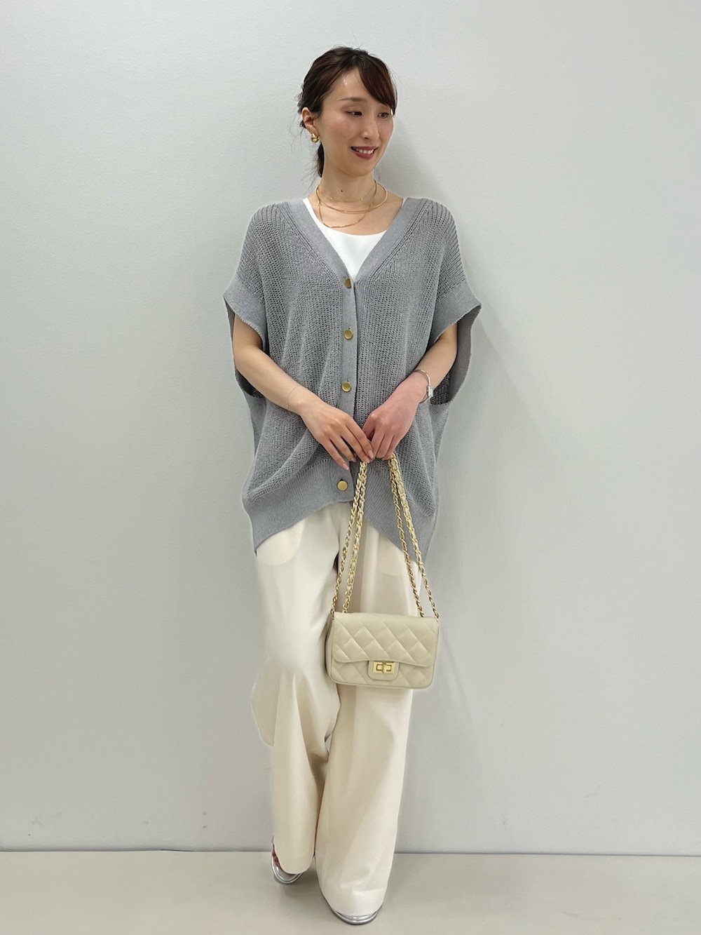 グレー系のベスト、ホワイト系のタンクトップ、ホワイト系のその他パンツを着用したレディースの春コーディネートの2枚目の写真