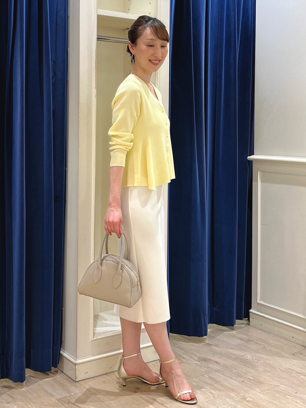 ベージュ系のカーディガン/ボレロ、ホワイト系のスカート、ベージュ系のボストンバッグを着用したレディースの春コーディネートの9枚目の写真