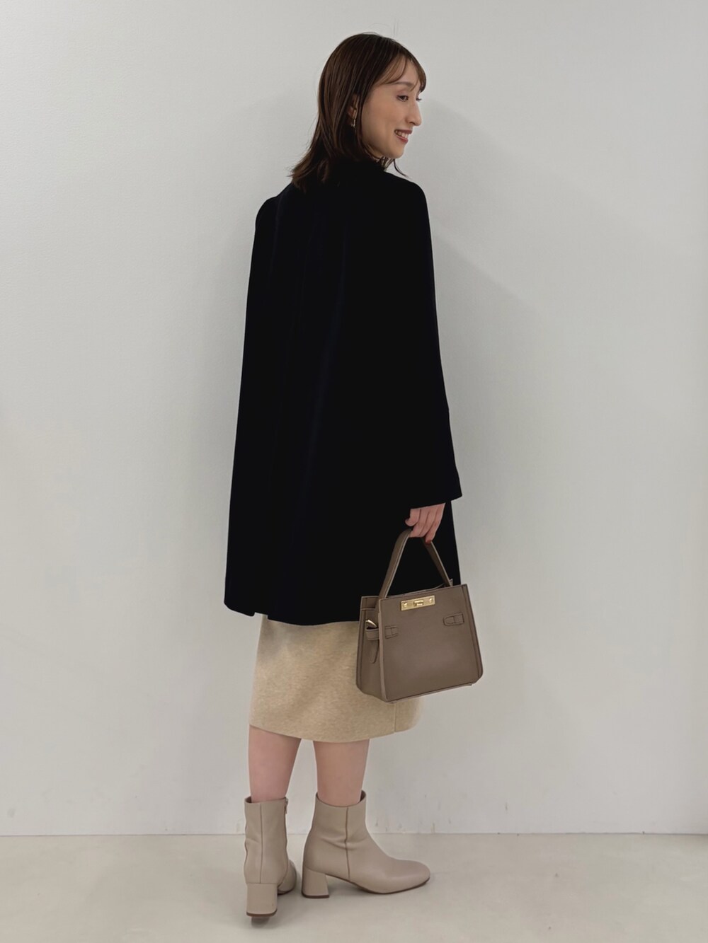 ブルー系のノーカラーコート、ベージュ系のワンピース、ベージュ系のショルダーバッグを着用したレディースの秋コーディネートの10枚目の写真