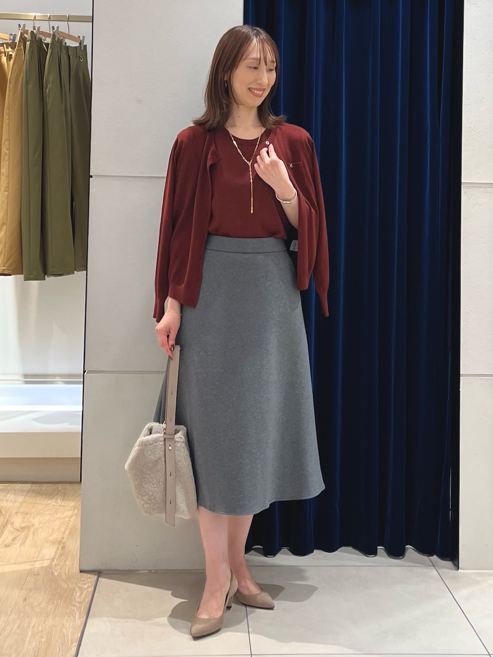 レッド系のニット/セーター、レッド系のカーディガン/ボレロ、グレー系のスカートを着用したレディースの秋コーディネートの5枚目の写真