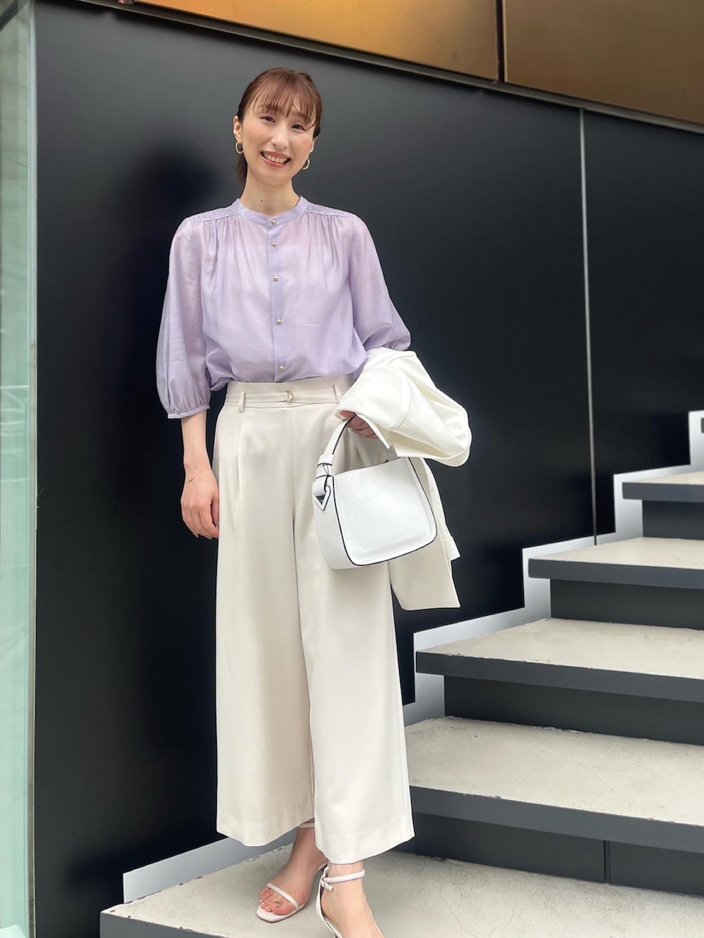 パープル系のシャツ/ブラウス、ホワイト系のその他パンツ、ブラック系のハンドバッグを着用したレディースの春コーディネートの2枚目の写真