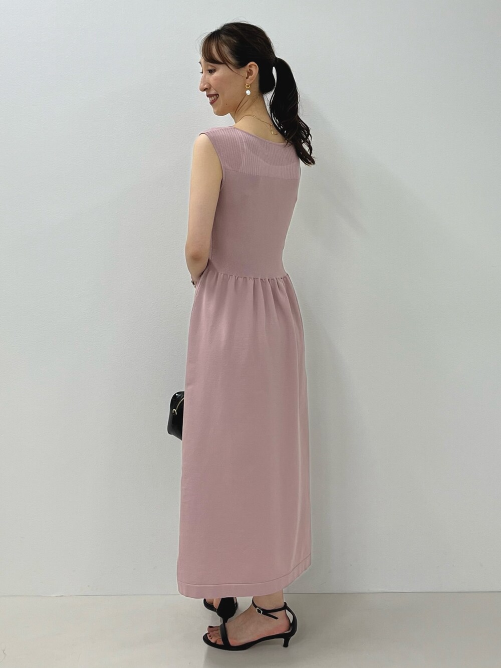 ピンク系のワンピース、ブラック系のサンダル、ゴールド系のピアス(両耳用)を着用したレディースの夏コーディネートの7枚目の写真