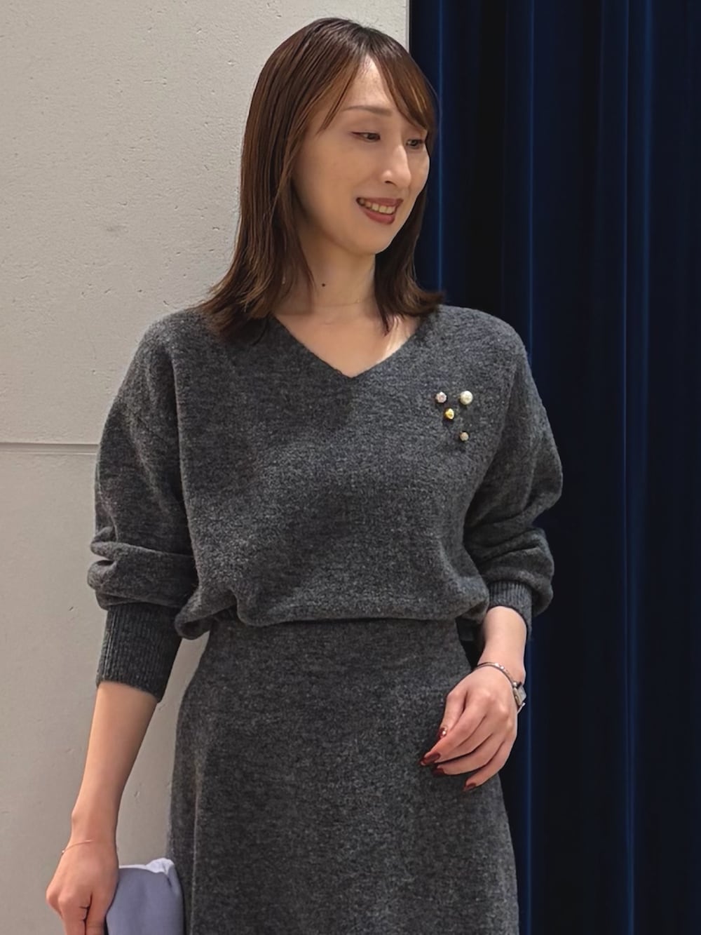 グレー系のニット/セーター、グレー系のスカート、ブラック系のショルダーバッグを着用したレディースの冬コーディネートの3枚目の写真