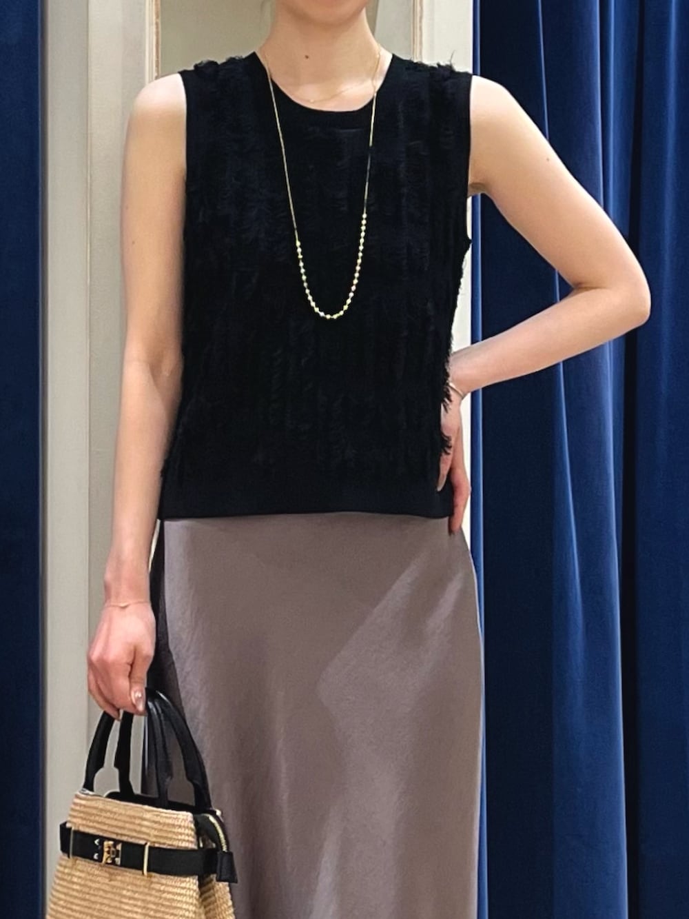 ブラック系のニット/セーター、グリーン系のスカート、ブラック系のかごバッグを着用したレディースの春コーディネートの4枚目の写真