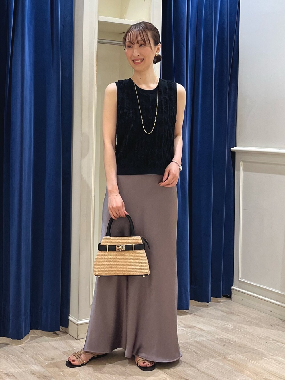 ブラック系のニット/セーター、グリーン系のスカート、ブラック系のかごバッグを着用したレディースの春コーディネートの3枚目の写真