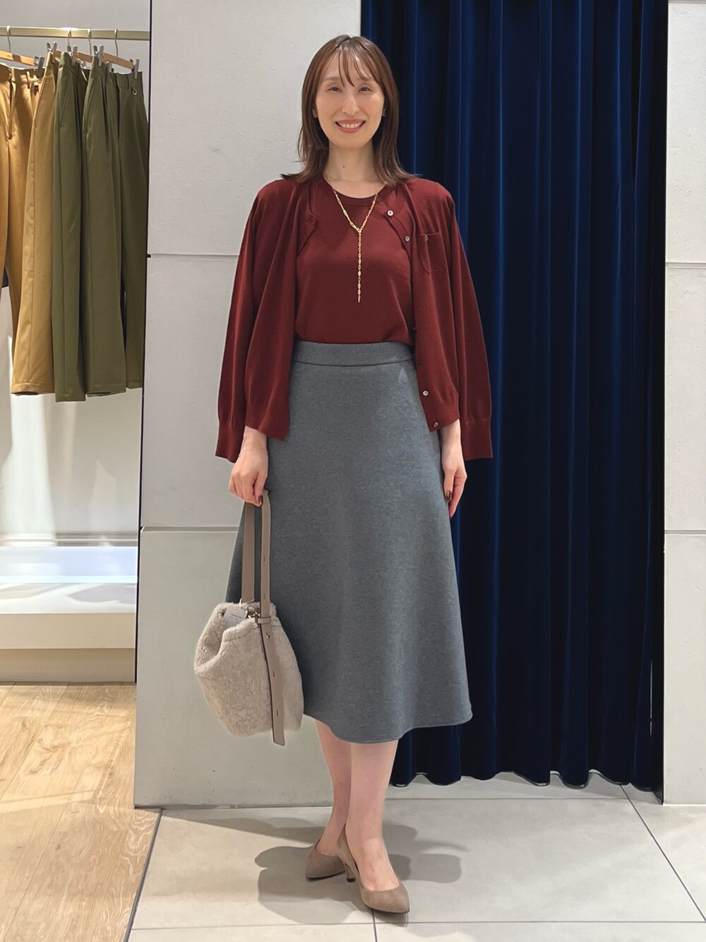 レッド系のニット/セーター、レッド系のカーディガン/ボレロ、グレー系のスカートを着用したレディースの秋コーディネートの7枚目の写真